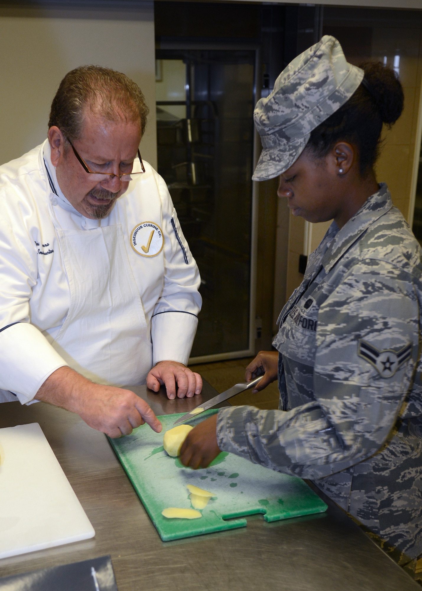 Chef consultant, Carlos Sierra, instructs Airman 1st Class Shayna Peggs, on how to slice a potato July 17, 2013, at Aviano Air Base, Italy. Peggs is a food service specialist with the 31st Force Support Squadron, and was one of five Airmen to receive hands-on training with two Le Cordon Bleu College of Culinary Arts chefs. (U.S. Air Force photo/Senior Airman Jessica Hines) 