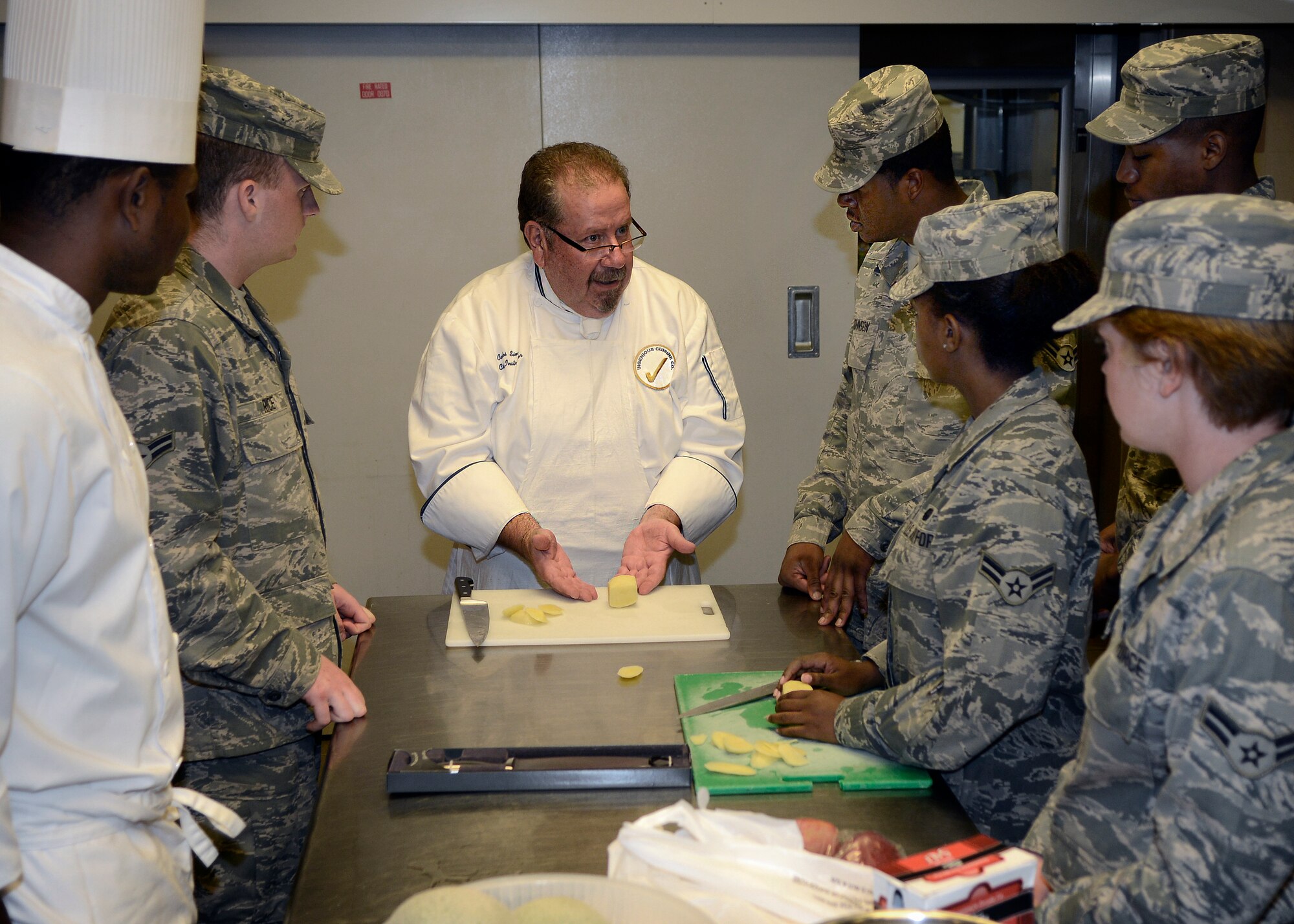 Carlos Sierra, chef consultant and former Le Cordon Bleu College of Culinary Arts instructor, explains different ways to cut vegetables July 17, 2013, at Aviano Air Base, Italy. Airmen from the 31st Force Support Squadron received a training opportunity to learn from two professionally trained culinary chefs. (U.S. Air Force photo/Senior Airman Jessica Hines)