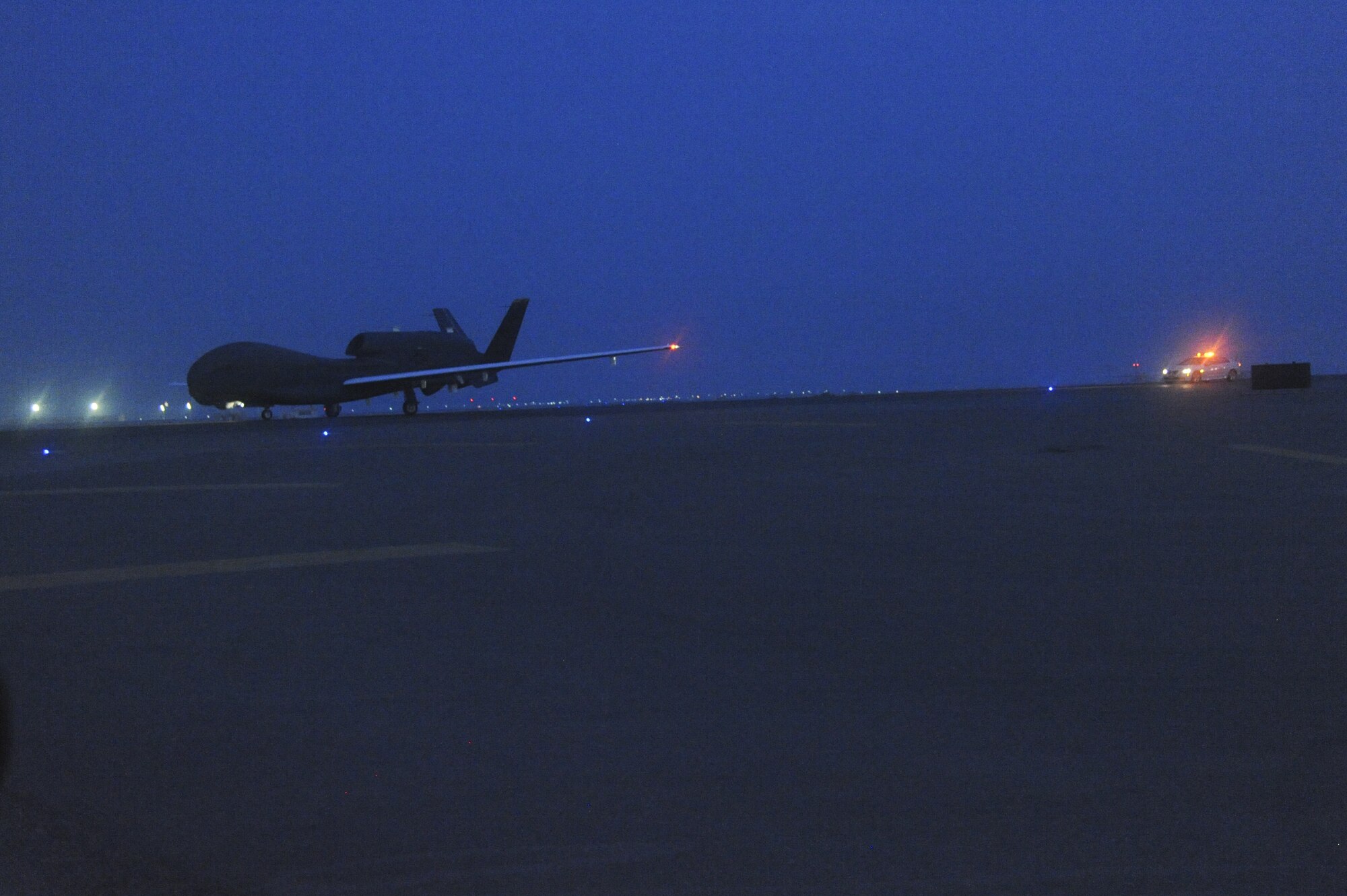 An RQ-4 Global Hawk assigned to the 99th Expeditionary Reconnaisance Squadron here, taxis down the runway using a computer program on board followed by a pilot in the chase car behind it at an undisclosed location in Southwest Asia July 17, 2013. The chase car makes sure the Global Hawk gets from landing to the ramp safely with no interruptions by watching for potential hazards. (U.S. Air Force photo by Senior Airman Jacob Morgan) 