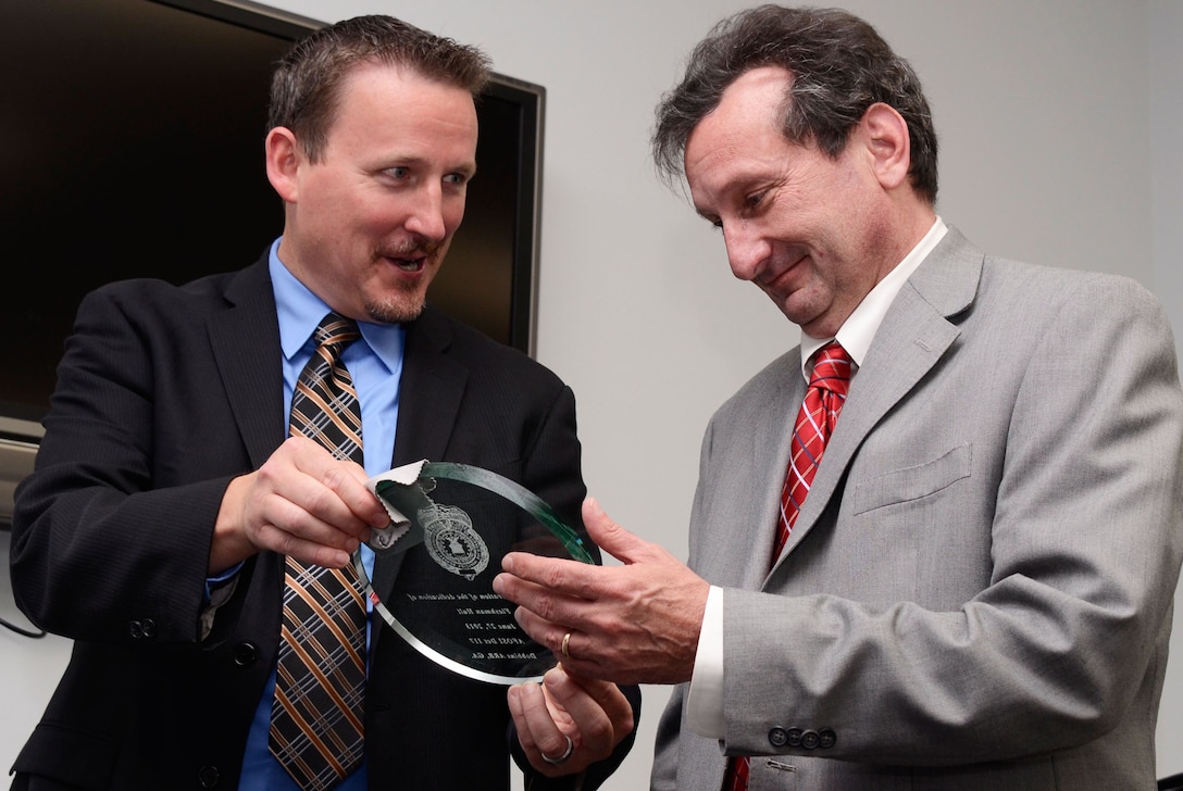 Lloyd F. Clark, special agent with the Air Force Office of Special Investigation honors former counter-terrorism OSI agent Jeff Fleshman with a memento marking a hall dedicated in his name at a ceremony held on Dobbins Air Reserve Base, Ga. June 27. Fleshman was instrumental in the OSI relocation to their current facility. (U.S. Air Force photo/Don Peek)
