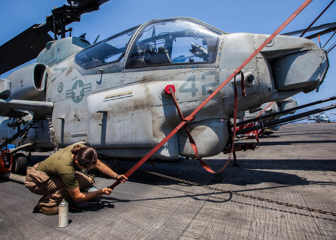 U.S. Marine Corps Cpl. Celia Trout a UH-1N Huey crew chief assigned to Marine Medium Tiltrotor Squadron (VMM) 266 (Reinforced), 26th Marine Expeditionary Unit (MEU), performs corrosion control on n AH-1W Super Cobra on the flight deck of the USS Kearsarge (LHD 3), at sea, July 20, 2013. The 26th MEU is a Marine Air-Ground Task Force forward-deployed to the U.S. 5th Fleet area of responsibility aboard the Kearsarge Amphibious Ready Group serving as a sea-based, expeditionary crisis response force capable of conducting amphibious operations across the full range of military operations. (U.S. Marine Corps photo by Sgt. Christopher Q. Stone, 26th MEU Combat Camera/Released)