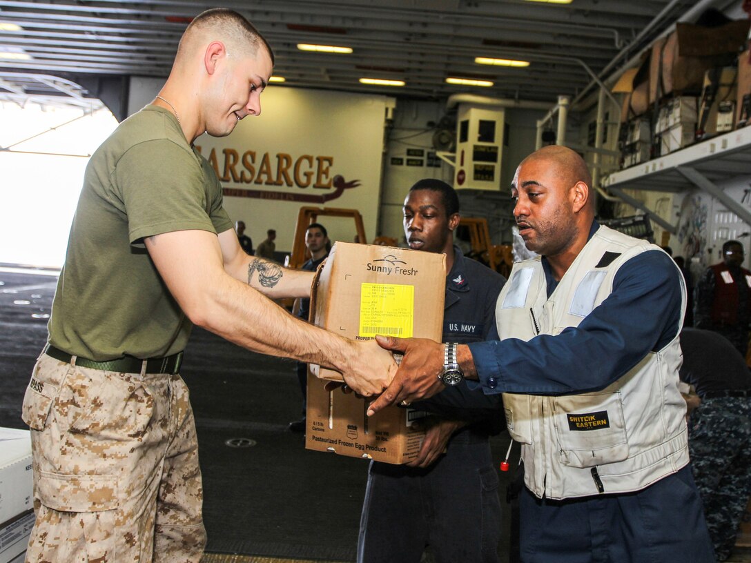 U.S. Marine Corps Sgt. William Repass, 26th Marine Expeditionary Unit (MEU) assistant headquarters commandant, helps move boxes of frozen goods during a resupply, in the hangar bay of the the USS Kearsarge (LHD 3), while underway, July 20, 2013. The 26th MEU is a Marine Air-Ground Task Force forward-deployed to the U.S. 5th Fleet area of responsibility aboard the Kearsarge Amphibious Ready Group serving as a sea-based, expeditionary crisis response force capable of conducting amphibious operations across the full range of military operations. (U.S. Marine Corps photo by Cpl. Kyle N. Runnels/Released)
