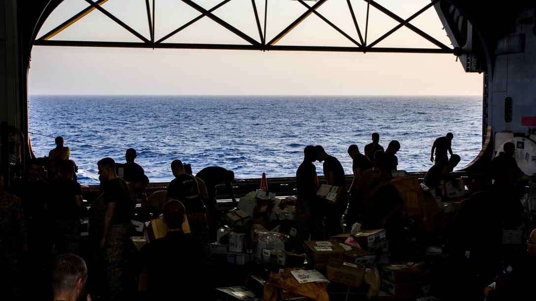 U.S. Marines assigned to 26th Marine Expeditionary Unit (MEU), sort mail in the hanger bay of the USS Kearsarge (LHD 3) after a resupply at sea, July 20, 2013. The ship received 136 pallets of mail, the largest shipment on this deployment. The 26th MEU is a Marine Air-Ground Task Force forward-deployed to the U.S. 5th Fleet area of responsibility aboard the Kearsarge Amphibious Ready Group serving as a sea-based, expeditionary crisis response force capable of conducting amphibious operations across the full range of military operations. (U.S. Marine Corps photo by Sgt. Christopher Q. Stone, 26th MEU Combat Camera/Released)