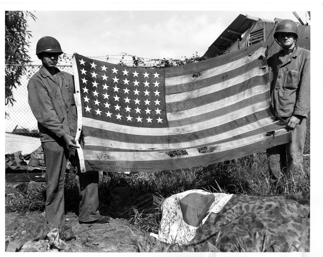 Marines display the American flag for a photograph shortly after securing a beachhead during the liberation of Guam July 21, 1944.  Guam concluded this year’s 69th Liberation celebration on Sunday with the Liberation Day Parade, the culminating event in a series of ceremonies and celebrations across the island.  Marine Corps Activity Guam Marines participated in and supported liberation events to honor their shared history with island residents, as Marines landed on Guam to free local Chamorros from Japanese occupation in World War II.  (Official U.S. Marine Corps photo by Sgt. John Raufmann)  