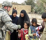 Lt. Col. David M. Lowe of Dixon, Mo., 35th Engineer Brigade judge advocate general officer, hands out Mardi Gras beads, stuffed animals and school supplies to more than 100 Iraqi children during a humanitarian mission with the Soldiers of the Louisiana National Guard's 769th Engineer Battalion of Baton Rouge, La. The Mardi Gras supplies were sent by Soldiers' Angels, a nation-wide organization, in effort to spread a little holiday cheer to the deployed Soldiers.