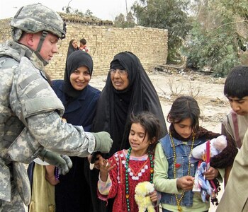 Lt. Col. David M. Lowe of Dixon, Mo., 35th Engineer Brigade judge advocate general officer, hands out Mardi Gras beads, stuffed animals and school supplies to more than 100 Iraqi children during a humanitarian mission with the Soldiers of the Louisiana National Guard's 769th Engineer Battalion of Baton Rouge, La. The Mardi Gras supplies were sent by Soldiers' Angels, a nation-wide organization, in effort to spread a little holiday cheer to the deployed Soldiers.