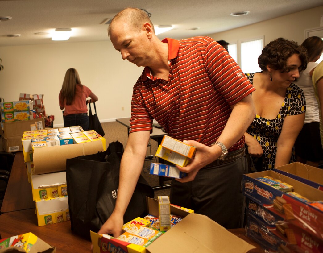 Matt Lynn, the regional development operations manager with Atlantic Marine Corps Communities employee fills a bag with food for needy children at an Atlantic Marine Corps Communities facility aboard Marine Corps Base Camp Lejeune, July 9. The food was donated by staff members to United Way’s Children Healthy Eating on Weekends program, a program that provides meals for underprivileged youth during the school year and throughout the summer. In addition to providing food to the program, Atlantic Marine Corps Communities gave a $500 check to the Camp Lejeune Dependent’s School Child Nutrition program, a separate program that provides meals to base youth when school is not in session.