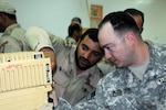 Maj. Brian Peterson, operations observer controller/trainer, 2nd battalion, 1st Squadron, 299th Cavalry Regiment, looks at a Jaguar radio with a Royal Saudi Land Force Soldier in a training session during Friendship One 2009, Feb. 21.