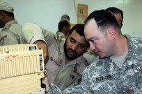 Maj. Brian Peterson, operations observer controller/trainer, 2nd battalion, 1st Squadron, 299th Cavalry Regiment, looks at a Jaguar radio with a Royal Saudi Land Force Soldier in a training session during Friendship One 2009, Feb. 21.