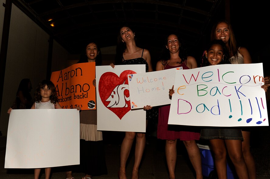 Family and friends of returning U.S. Air Force members from the 961st Airborne Air Control Squadron hold up signs welcoming them home on Kadena Air Base, Japan, July 19, 2013. Twenty-four service members assigned to the 961st AACS returned to home station after being deployed to Southwest Asia for roughly 90 days. (U.S. Air Force photo by Senior Airman Maeson L. Elleman/Released)
