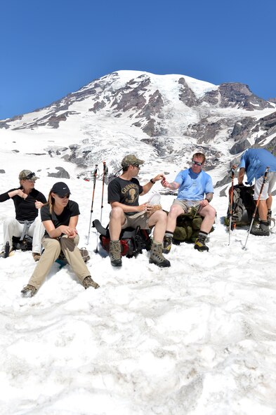 Master Sgt. Doug Neville and Staff Sgt. Brian Wadtke, 22nd Special Tactics Squadron combat controllers, share snacks during one of the rest stops along the route to Camp Muir, July 20, 2013. Staff Sgt. Savanna Wadtke, 627th Force Support Squadron commander’s support staff member, joined her husband to provide motivational support. (U.S. Air Force photo/Staff Sgt. Jason Truskowski)