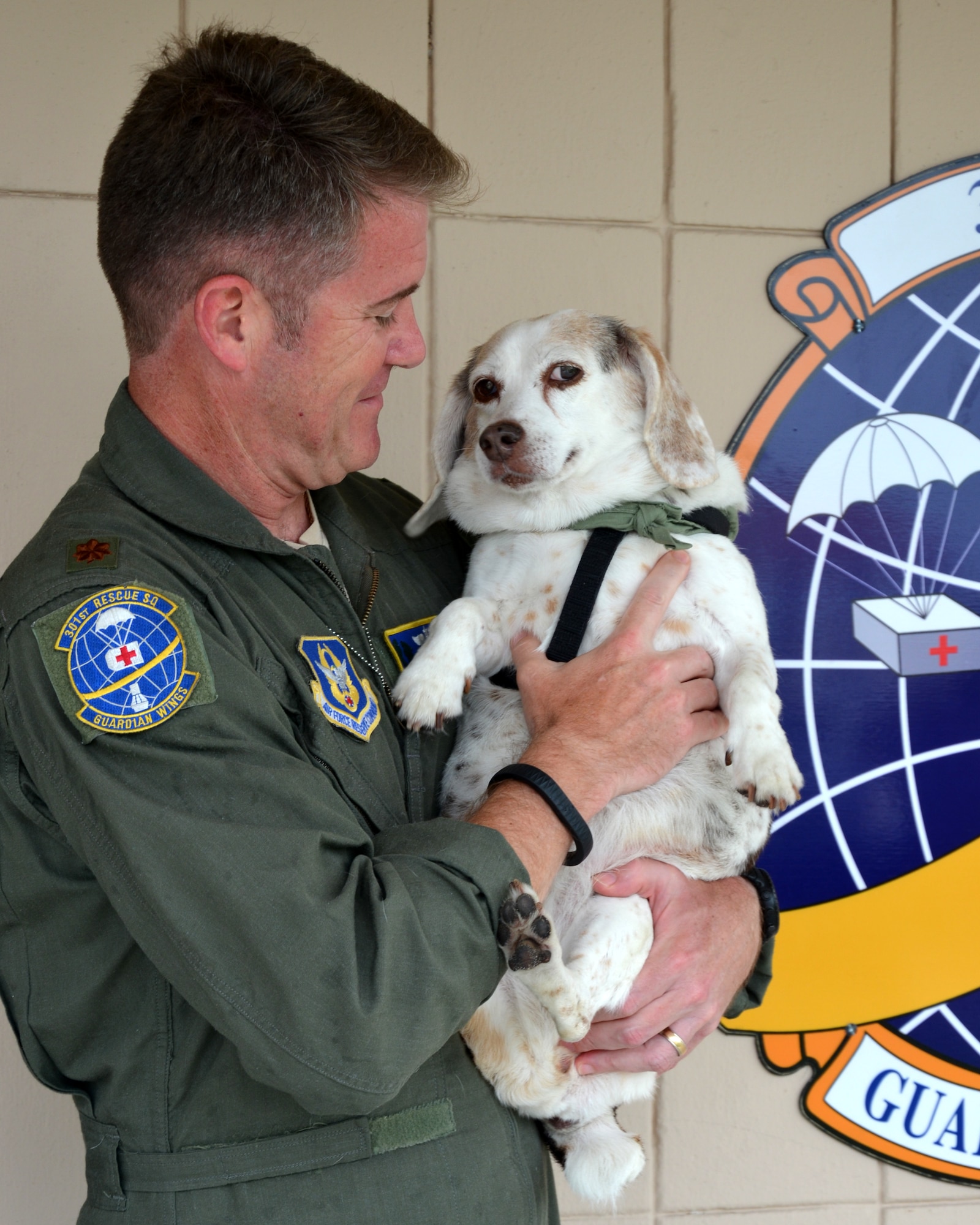Maj. Mike Brasher, 920th Rescue Wing helicopter pilot, holds his best friend and fellow crewmember, Katrina, during a recent visit to the 301st Rescue Squadron. Katrina is a 13-year-old beagle who became the squadron's mascot after the courageous canine assisted him and fellow crewmembers with rescuing victims of Hurricane Katrina during the tragic aftermath in 2005. After the beagle assisted with shepherding victims onto the helicopter for evacuation from one of the area?s overpasses, she became the last creature standing and Brasher?s crew swept her up in the helicopter. After dropping her off to safety, it took Brasher and his wife Melanie a month of searching until they found the dog again, and adopted her from a shelter where she ended up in Arizona. Thirty-two Airmen from the 920th Rescue Wing were awarded air medals for their outstanding performance in New Orleans where they rescued 1,043 people and some odd number of pets. (U.S. Air Force photo/Maj. Cathleen Snow)