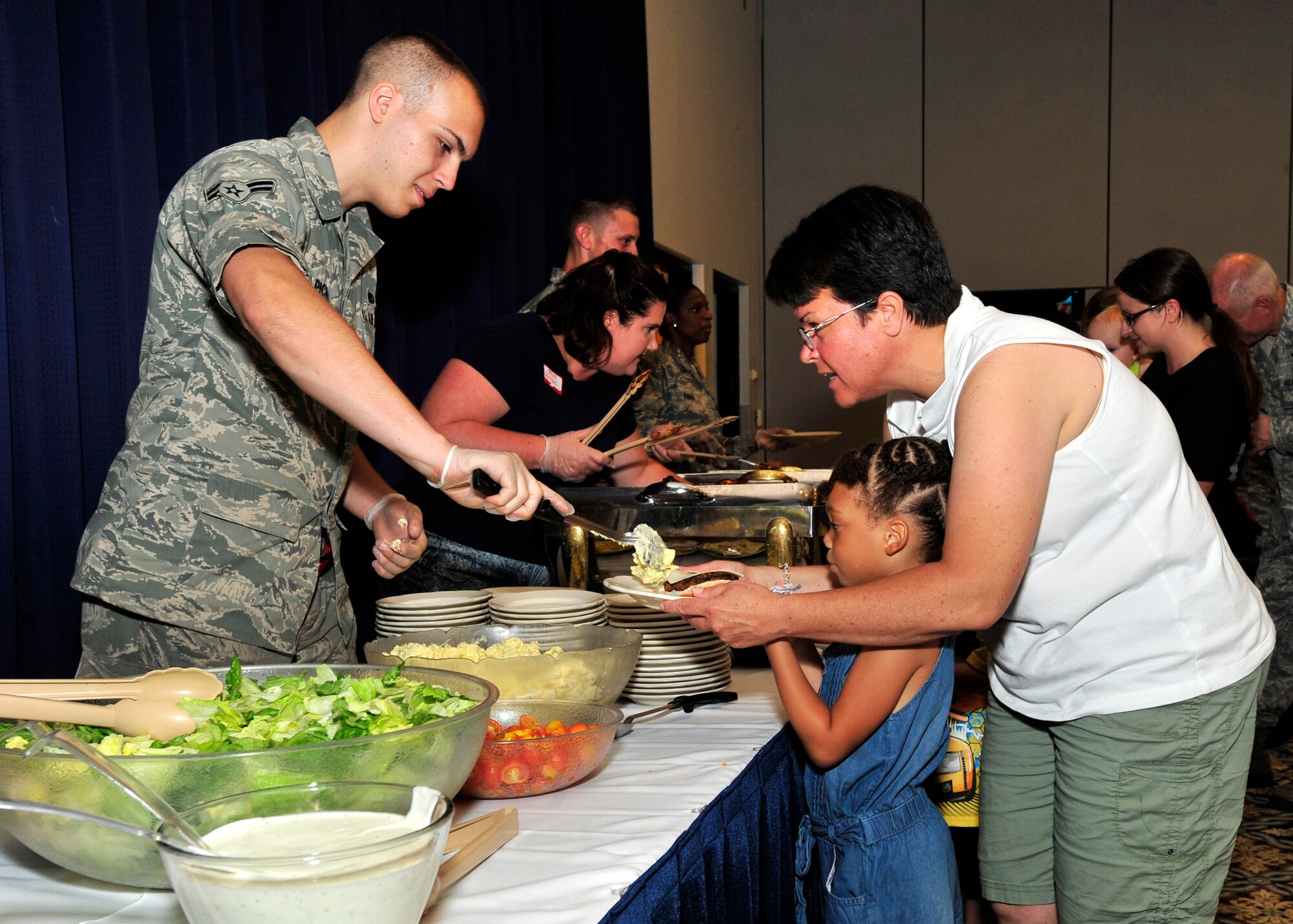 Lt. Col. Heather Cook, 436th Aerial Port Squadron commander, left, helps Lalah Young get food at the Deployed Spouses Dinner July 18, 2013, at The Landings on Dover Air Force Base, Del. The dinner provided spouses and children of deployed Team Dover members the opportunity to enjoy a meal, games and to interact with squadron leadership. (U.S. Air Force photo/Tech. Sgt. Chuck Walker)