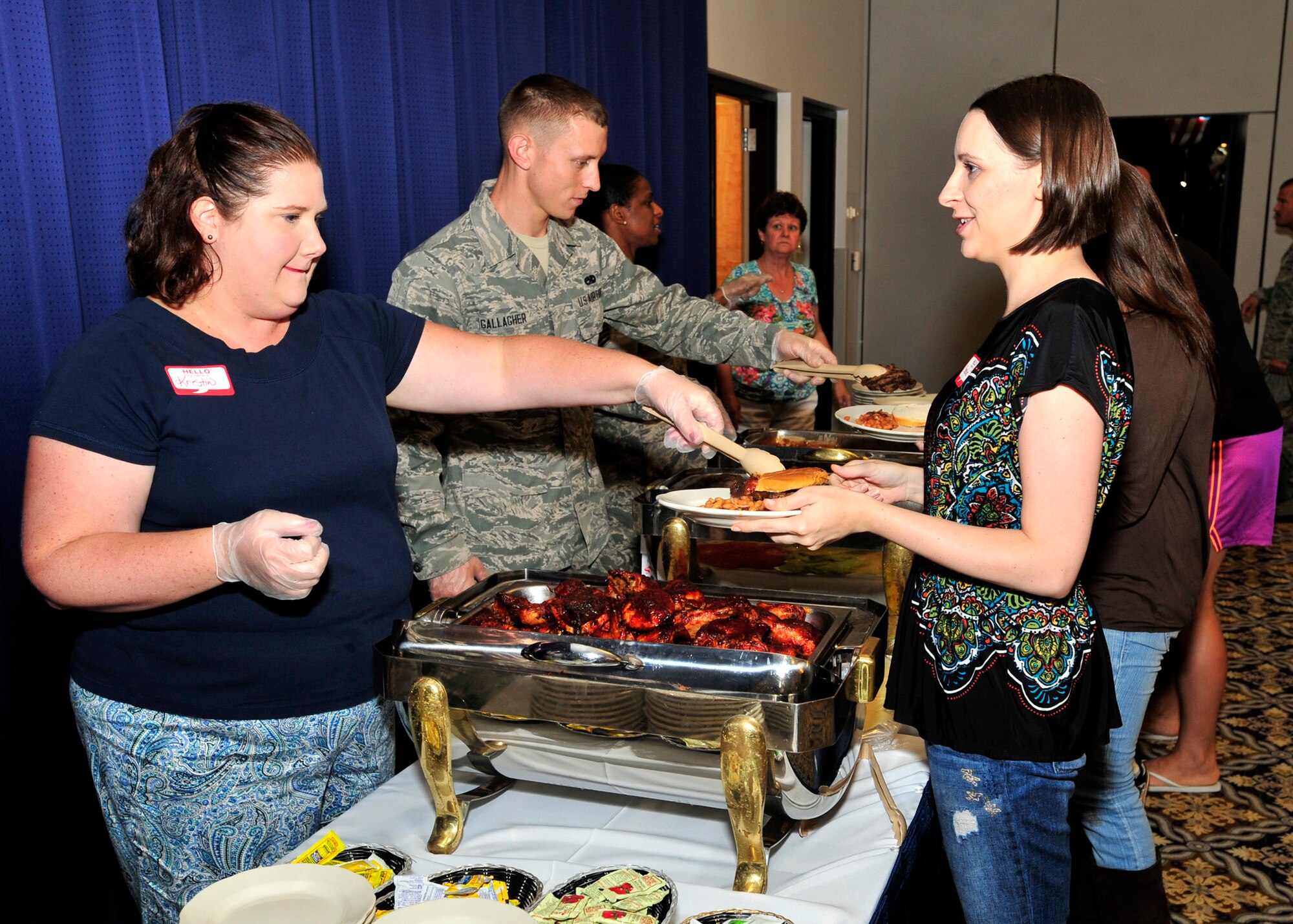 Kristin Moore, wife of Col. Rick Moore, 436th Airlift Wing commander, dishes out barbeque chicken to Shasta Lantz at the Deployed Spouses Dinner July 18, 2013, at The Landings on Dover Air Force Base, Del. The dinner provided spouses and children of deployed family members the opportunity to enjoy food, games and gather information from base support agencies. (U.S. Air Force photo/Tech. Sgt. Chuck Walker)