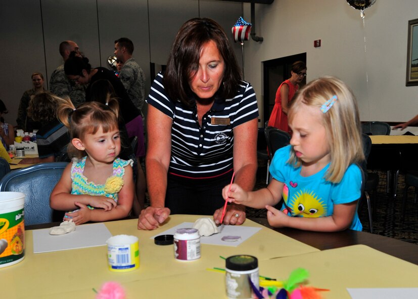 Troi Reppart, wife of Col. Thomas Reppart, 436th Mission Support Group commander, helps Payton Hawkins, left, and Olivia Hawkins with a craft July 18, 2013, at The Landings on Dover Air Force Base, Del. Team Dover hosted a Deployed Spouses Dinner that allowed spouses and children of deployed members the opportunity to enjoy a meal, play games and receive information from base support agencies. (U.S. Air Force photo/Tech. Sgt. Chuck Walker)
