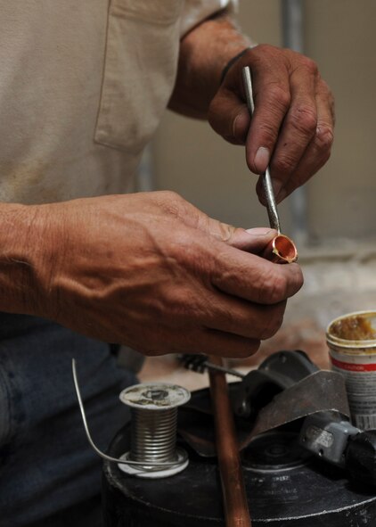 Jim Tyndall, Plumbing Design and Installation Inc. master plumber, applies glue to copper piping while installing plumbing in the Jefferson Chambers Dormitory during a renovation project at Ellsworth Air Force Base, S.D., July 15, 2013. The renovation project provides Airmen with new appliances and more countertop space to prepare and cook meals. (U.S. Air Force photo by Airman 1st Class Anania Tekurio/Released)