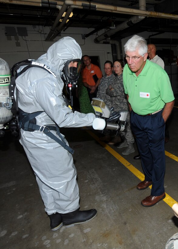 Staff Sgt. Aaron Waite, 28th Medical Operations Squadron bioenvironmental engineering technician, explains his job to Dr. Roger Wilson, 28th Medical Group honorary commander, during a Military Affairs Committee luncheon at the 28th Medical Group on Ellsworth Air Force Base, S.D., July 18, 2013. Waite is using a Surveillance and Measurement 940 radiation detector in a Level B hazardous material suit to illustrate one of his many roles as a bioenvironmental engineering technician. (U.S. Air Force photo by Airman 1st Class Anania Tekurio/Released)
