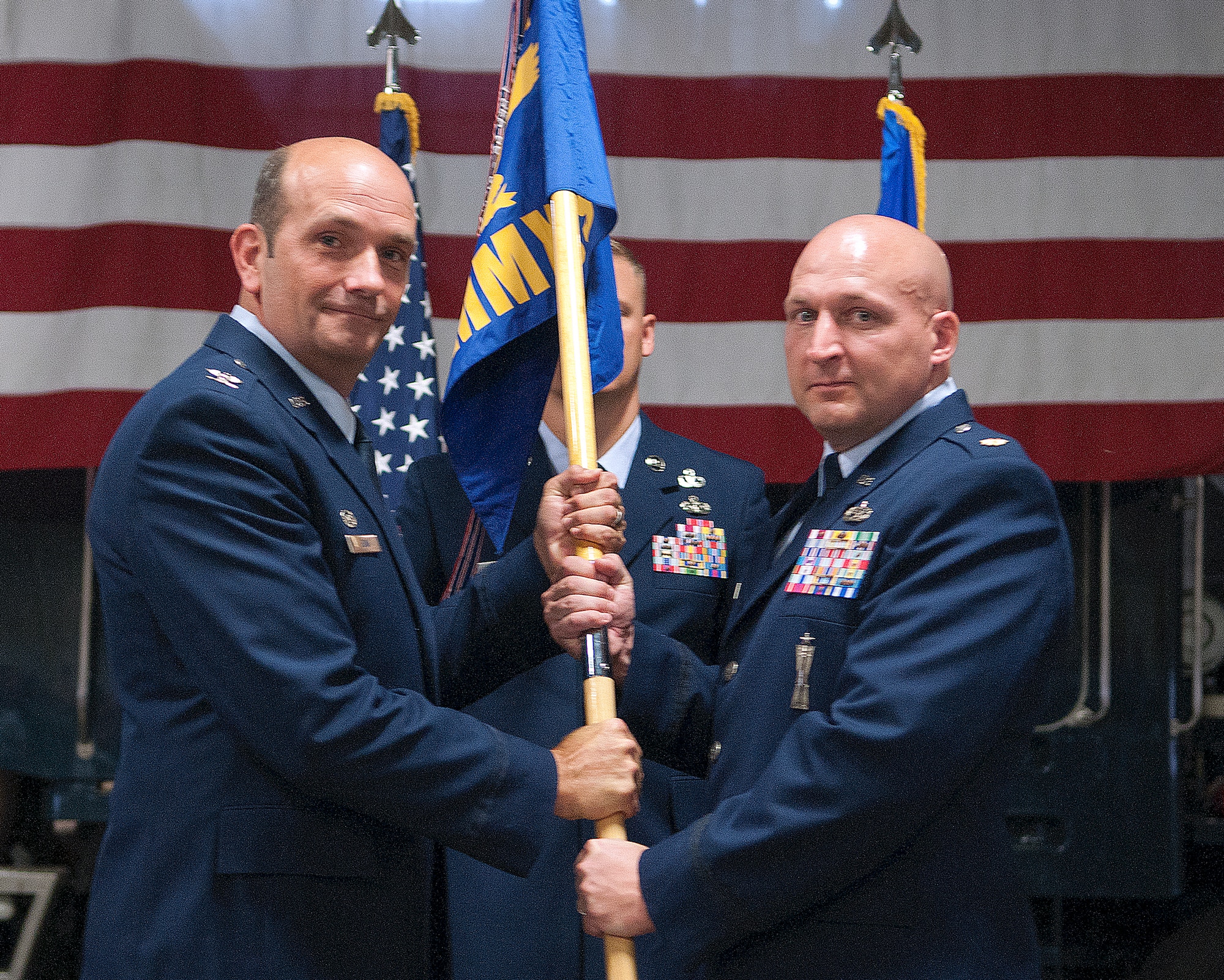 Col. Trevor Flint, 90th Maintenance Group commander, passes the 90th Missile Maintenance Squadron guidon to Maj. Dale Overholts as he assumes command of the squadron during a change of command ceremony in the 90th MXG maintenance bay, F.E. Warren Air Force Base, Wyo., July 12, 2013. (U.S. Air Force photo by R.J. Oriez)
