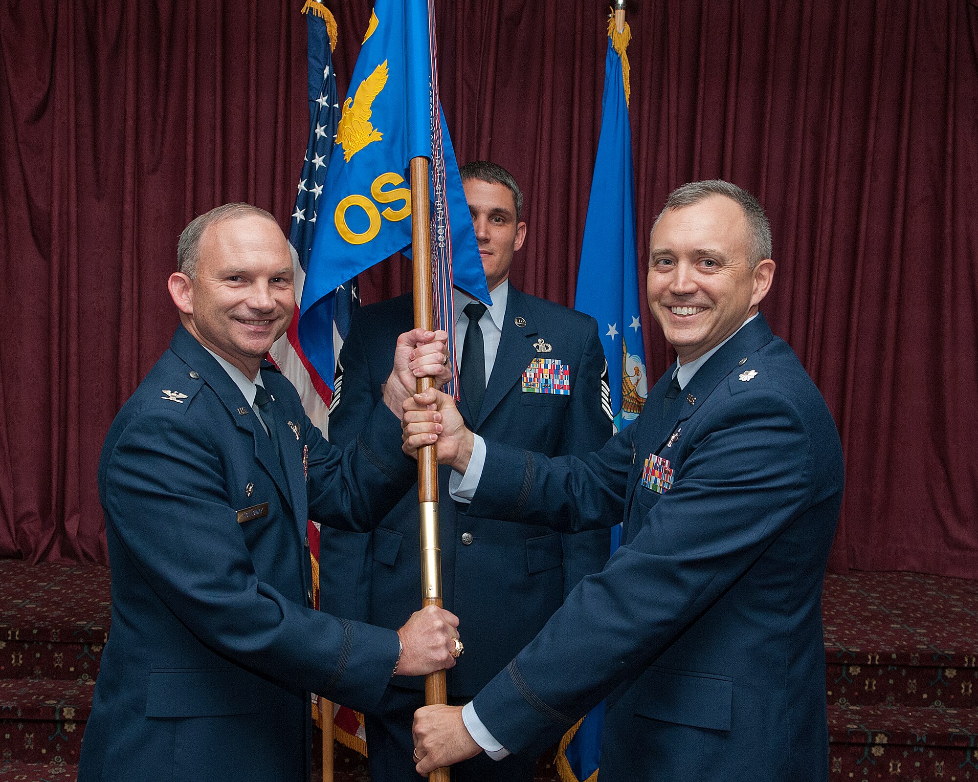 Col. Donnie Holloway, 90th Operations Group commander, passes the 90th Operations Support Squadron guidon to Lt. Col. Barry Little as he assumes command of the squadron during a change of command ceremony in the Trail’s End Club, F.E. Warren Air Force Base, Wyo., July 12, 2013. (U.S. Air Force photo by R.J. Oriez)