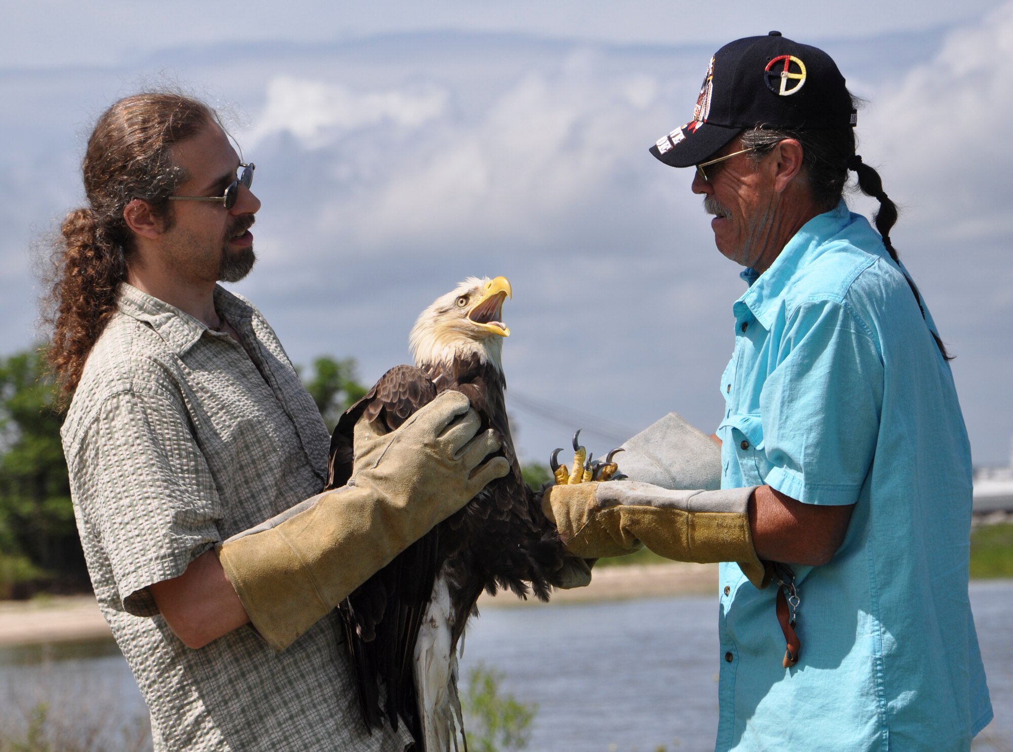 Dr. Tony Poutous, veterinarian, and James Beamer, wildlife rehabilitator, position an eagle to receive identification bands and measurements on Fort Eustis, Va., June 22, 2013. Poutous and Beamer helped rehabilitate the eagle so she could be released back into her natural environment.  (U.S. Air Force photo by Tech. Sgt. April Wickes/Released) 