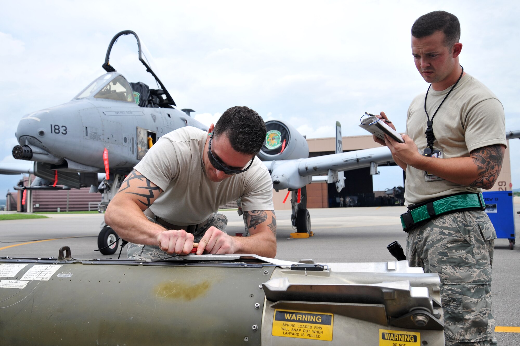 Senior Airman Matthew Miller, left, 25th Aircraft Maintenance Unit weapons loader, ensures a CBU-103 bomb is ready to be loaded on an A-10 Thunderbolt during a quarterly weapons load crew competition at Osan Air Base, Republic of Korea, July 19, 2013. In addition to the weapons loading, crews are also inspected on their dress and appearance, and given a written examination. (U.S. Air Force photo/Staff Sgt. Emerson Nuñez)
