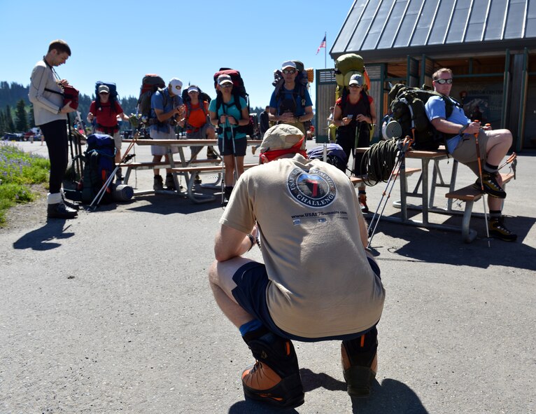 Maj. Rob Marshall, CV-22 Osprey pilot stationed at Amarillo, Texas, crouches down as he reads an inspirational quote to the 12-man Mount Rainer summit team in Paradise, Wash., July 20, 2013. Marshall is one of the co-founders of the U.S. Air Force Seven Summits Challenge and a team leader for the “Climbing for Warriors” project.  (U.S. Air Force photo/Staff Sgt. Jason Truskowski)
