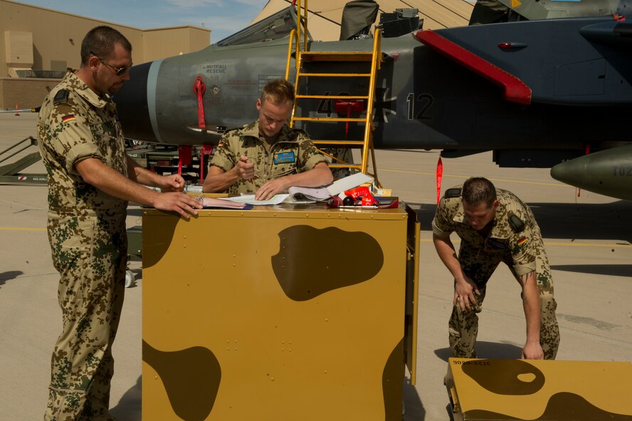 German Air Force Staff Sgt. Esser Benjamin, Airman 1st Class Enrico Reich and Staff Sgt. Mark Bender, German Air Force Flying Training Center weapons load crew members, prepare to load inert missiles onto a Tornado aircraft during a quarterly load crew competition at Holloman Air Force Base, N.M., July 19. The GAF competed in the load crew competition to have their skills evaluated alongside F-22 Raptor aircraft and MQ-9 Reaper aircraft load crews. For the competition, points are awarded during the weapons-loading, tool kit inspection, and uniform inspection. (U.S. Air Force photo by Airman 1st Class Chase Cannon/Released)