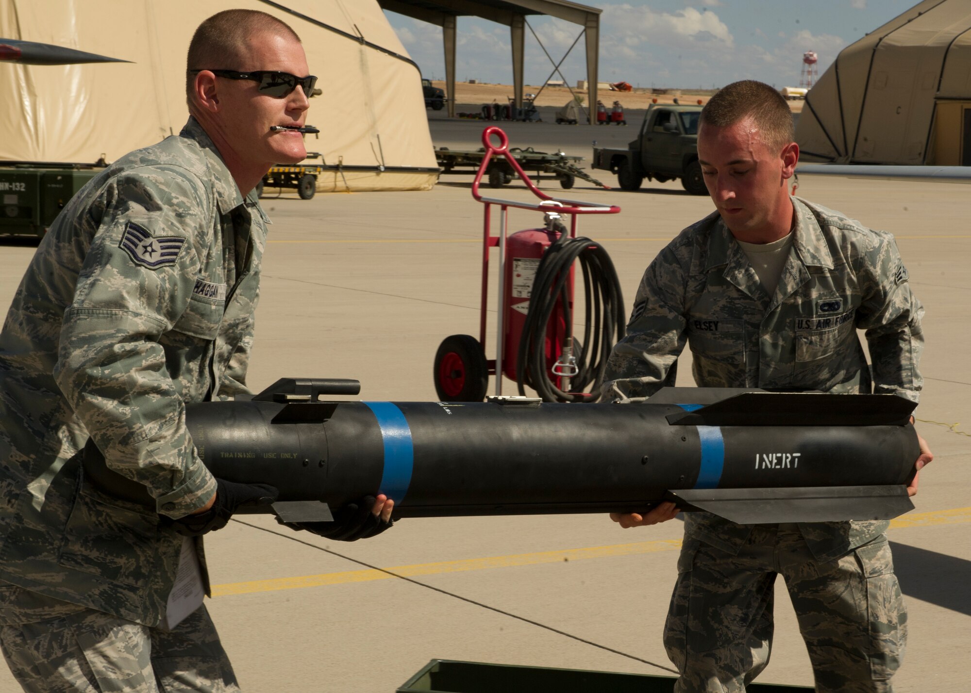 Staff Sgt. Patrick Haggan and Senior Airman Thaddeus Elsey, both 849th Aircraft Maintenance Squadron MQ-1 Predator weapons load crew members, prepare to load an inert missile during a quarterly load-crew competition at Holloman Air Force Base, N.M., July 19. The 849th AMXS pitted two MQ-1 Predator aircraft load crews against each other to evaluate who could prepare the aircraft for combat the quickest and with the fewest procedural errors. (U.S. Air Force photo by Airman 1st Class Chase Cannon/Released)