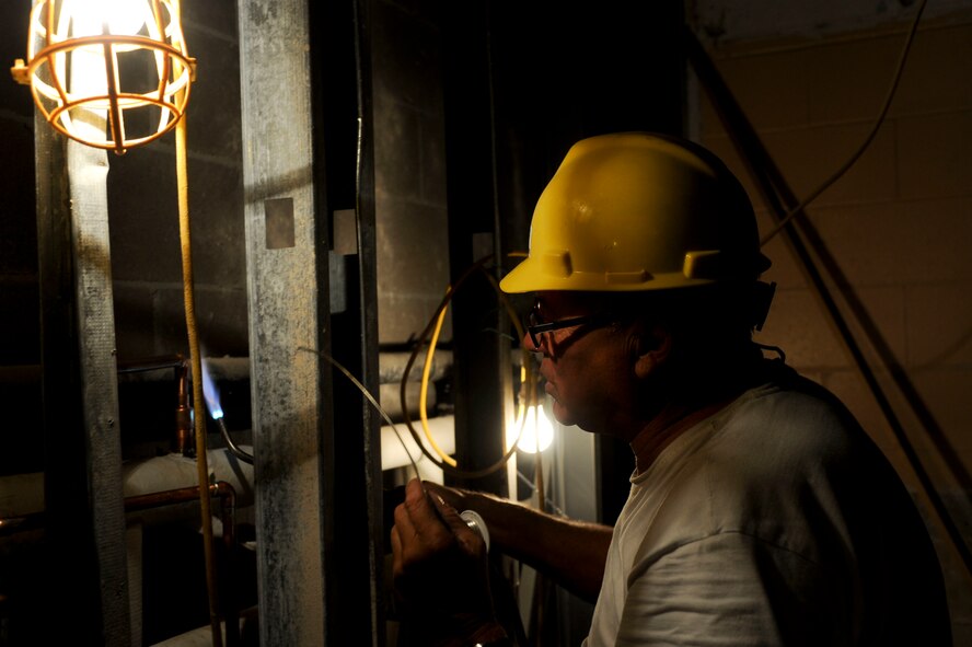 Jim Tyndall, Plumbing Design and Installation Inc. master plumber, burns through copper piping during plumbing installation of the Jefferson Chambers Dormitory kitchenette at Ellsworth Air Force Base, S.D., July 15, 2013. Old cast iron plumbing is now being replaced with up-to-date polyvinyl chloride piping in every dorm kitchenette to provide for a leak free plumbing system. (U.S. Air Force photo by Airman 1st Class Anania Tekurio/Released)