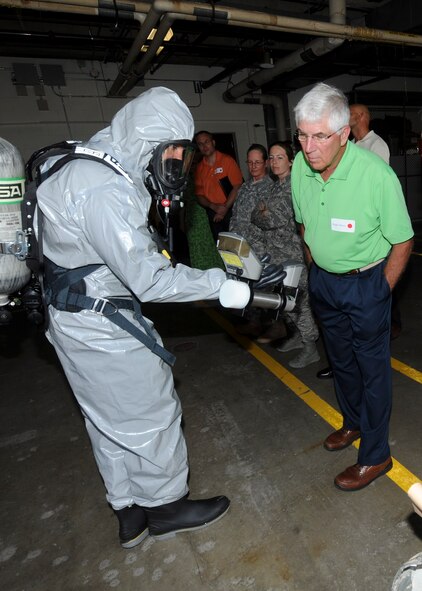 Staff Sgt. Aaron Waite, 28th Medical Operations Squadron bioenvironmental engineering technician, explains his job to Dr. Roger Wilson, 28th Medical Group honorary commander, during a Military Affairs Committee luncheon at the 28th Medical Group on Ellsworth Air Force Base, S.D., July 18, 2013. Waite is using a Surveillance and Measurement 940 radiation detector in a Level B hazardous material suit to illustrate one of his many roles as a bioenvironmental engineering technician. (U.S. Air Force photo by Airman 1st Class Anania Tekurio/Released)