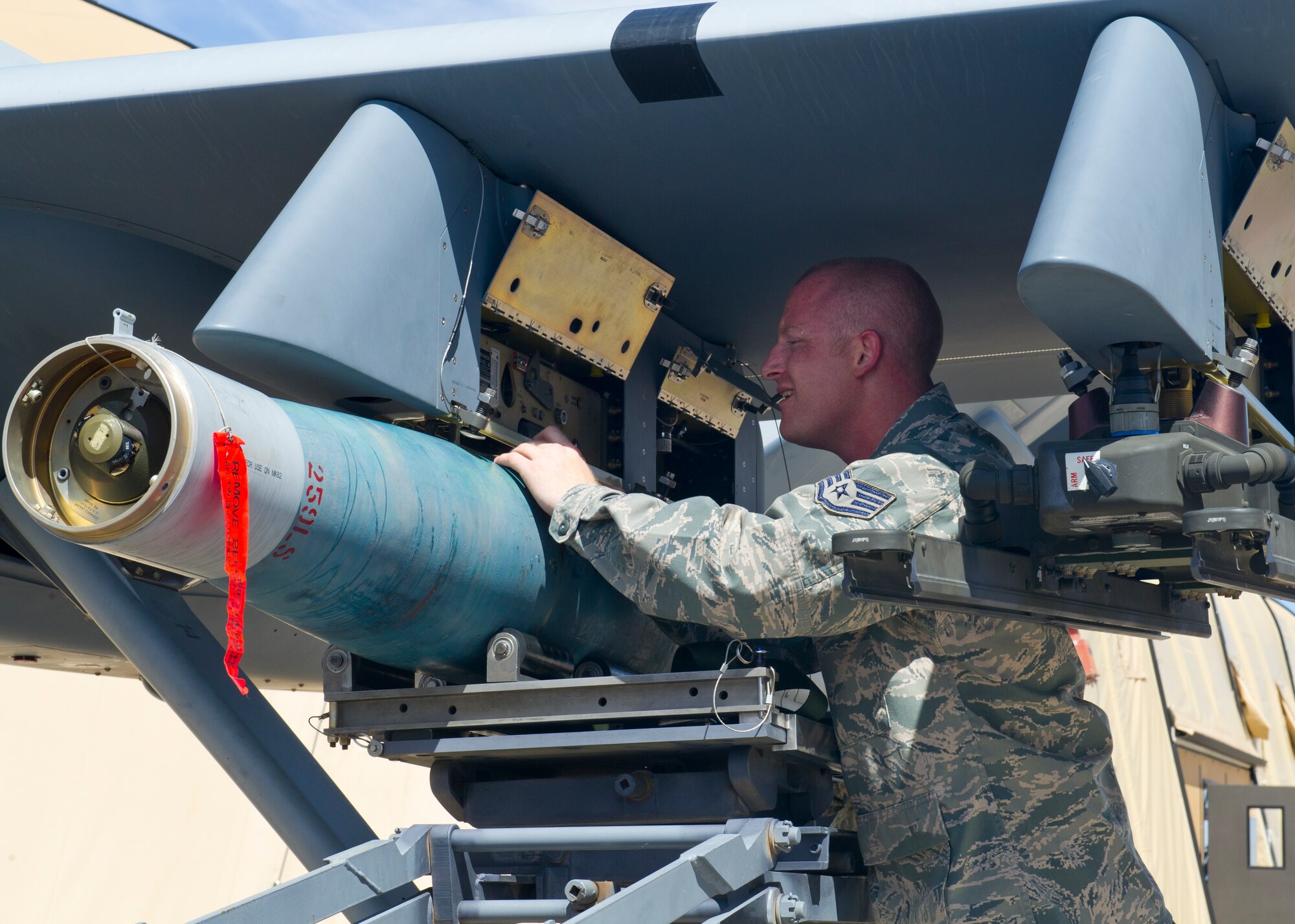 Staff Sgt. Jack MacArthur, 849th Aircraft Maintenance Squadron weapons load crew chief, locks an inert bomb onto an MQ-9 Reaper during the second quarter load crew competition at Holloman Air Force Base, N.M., July 19. The MQ-9 load crew participated in the load crew competition to have their skills evaluated alongside the F-22 Raptor and German Air Force Tornado aircraft load crews. For the competition, points are awarded during the weapons loading, tool kit inspection, and uniform inspection. (U.S. Air Force photos by Airman 1st Class Leah Murray/Released)