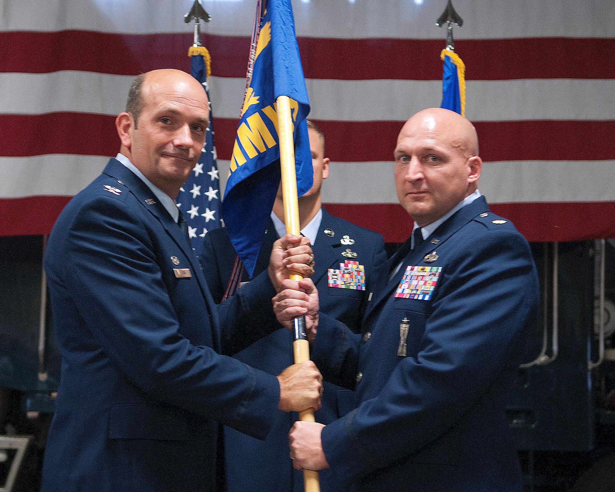 Col. Trevor Flint, 90th Maintenance Group commander, passes the 90th Missile Maintenance Squadron guidon to Maj. Dale Overholts as he assumes command of the squadron during a change of command ceremony in the 90th MXG maintenance bay, F.E. Warren Air Force Base, Wyo., July 12, 2013. (U.S. Air Force photo by R.J. Oriez)