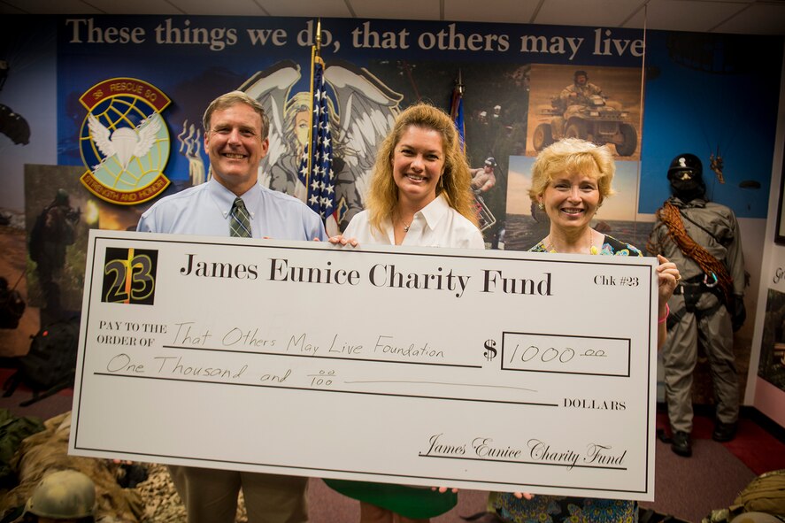 John and Tammy Eunice present a $1,000 check to Laura Lerdall (center), That Others May Live Foundation deputy executive director for operations, July 10, 2013, at Moody Air Force Base, Ga. The Eunice family used the presentation as their way of giving back to the rescue community after members of the 38th and 41st Rescue Squadrons helped recovery their son, James’, body after he drowned at a pond in January 2011. (U.S. Air Force photo by Staff Sgt. Jamal D. Sutter/Released)