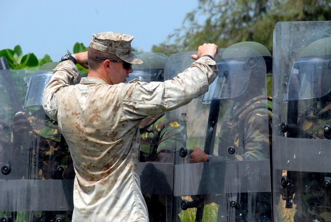 Sgt. Evan Wray, military policeman with Company Alpha, 4th Law Enforcement Battalion, demonstrate how to use a riot shield to Ghana Armed Forces 2nd Engineer Battalion soldiers during non-lethal training to the at the 48th Engineer Regiment Wajir Barracks in Accra, Ghana June 20 during Western Accord 2013.