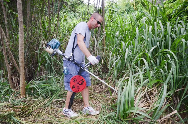 2nd Lt. Jeff Moses, officer in charge, Remain Behind Element, 2nd Battalion, 3rd Marine Regiment's remain behind element and native of Corpus Christi, TX, cuts grass at Heeia State Park, July 13, 2013. The Marines of the RBE, 2nd Bn., 3rd Marines and their family members joined the local community in clearing overgrown vegetation at the park. (U.S. Marine Corps photo by Kristen Wong)