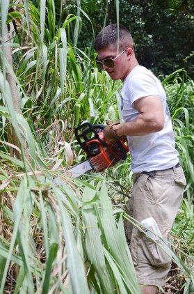 Pfc. Mitch Dornan, a Marine with Fox Company, 2nd Battalion, 3rd Marine Regiment, uses a chainsaw to remove excess foliage at Heeia State Park, July 13, 2013. The Marines of the Remain Behind Element, 2nd Bn., 3rd Marines and their family members joined the local community in clearing overgrown vegetation at the park. (U.S. Marine Corps photo by Kristen Wong)