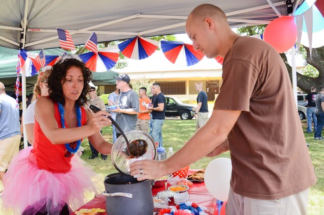 Rebecca Swinson, a team member of TuTu Delicious serves chili to Staff Sgt. Stephen Dosch, a production control Marine with Marine Aviation Logistics Squadron 24 during the Marine Aircraft Group 24 chili cook-off at Dewey Square, July 3, 2013. (U.S. Marine Corps photo by Kristen Wong)
