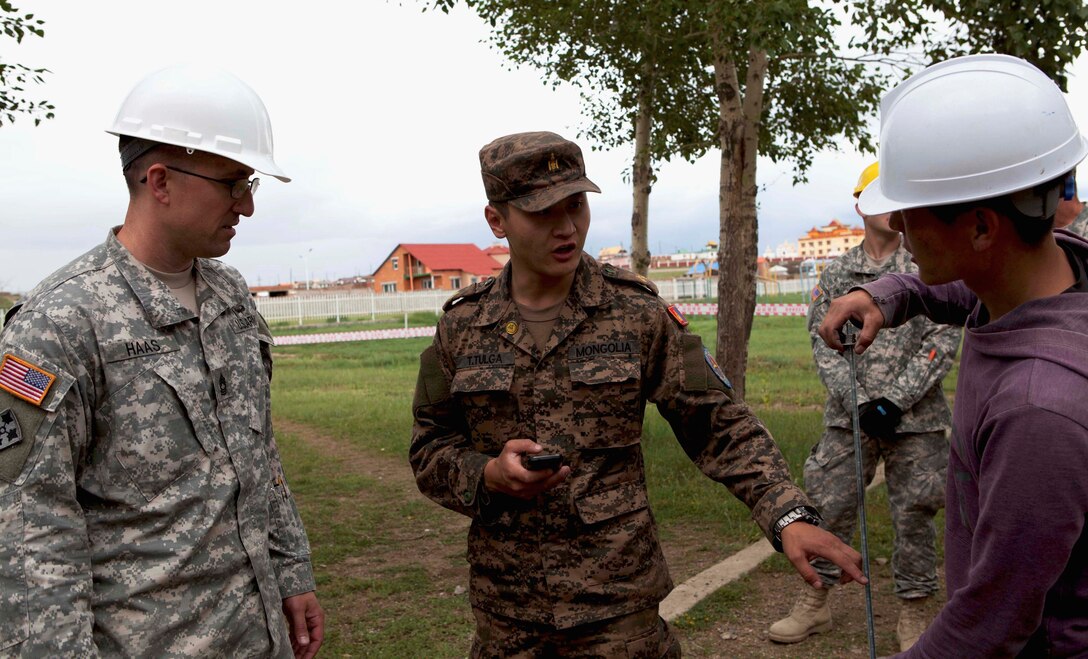 Army Master Sgt Andrew Haas, site foreman and operations sergeant with 96th Troops Command, Washington Army National Guard, stands aside as Mongolian Armed Forces 1st Lt. Tumurbataar Tulga, training officer for 017 Construction Regiment and Mongolian officer-in-charge at the site, provides instructions to one of his engineers at the Erdmiin Oyan High School renovation site, July 20. The MAF engineers are working alongside U.S. Marine and Washington Army National Guard counterparts to complete the school renovation project as part of Exercise Khaan Quest 2013, a regularly scheduled, multinational exercise co-sponsored this year by U.S. Marine Corps Forces Pacific, and hosted annually by the MAF. The intent of the ongoing engineering civic action program (ENCAP) project in Nalaikh is to provide valuable training for Mongolian and U.S. armed forces by boosting their interoperability, as well as demonstrate a mutual commitment to local community. 