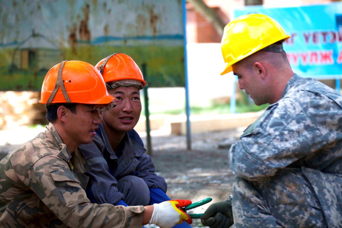 Mongolian Armed Forces Sgt. Gantugs Battsengel, a builder with the MAF's 017 Construction Unit, hands a pair of wire cutters to Army Sgt. Sean Belka, an engineer with 176th Engineer Company (Vertical), 96th Troop Command, Washington Army National Guard, Jul 20. The multinational team of engineers, which includes U.S. Marines with 9th Engineer Support Battalion, are working together to renovate Erdmiin Oyun High School in the Nalaikh district of Ulaanbaatar as part of Exercise Khaan Quest 2013, a regularly scheduled, multinational exercise co-sponsored this year by U.S. Marine Corps Forces Pacific, and hosted annually by the MAF. The intent of the ongoing engineering civic action program (ENCAP) project in Nalaikh is to provide valuable training for Mongolian and U.S. armed forces by boosting their interoperability, as well as demonstrate a mutual commitment to local community.
