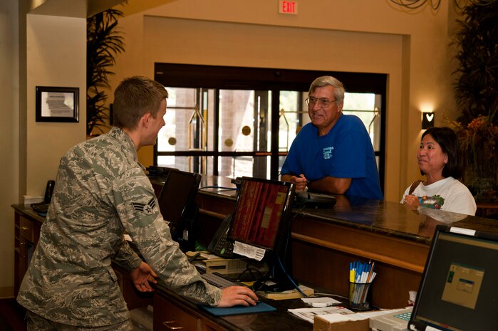 U.S. Air Force Senior Airman Angelo Cavaretta, 99th Force Support Squadron guest services representative, provides lodging information to Tom and Anh Szvorkm at the Nellis Inn July 18, 2013, at Nellis Air Force Base, Nev. The guest services representative is responsible for checking in guests as well as ensuring guests check out on time. (U.S. Air Force photo by Senior Airman Daniel Hughes)