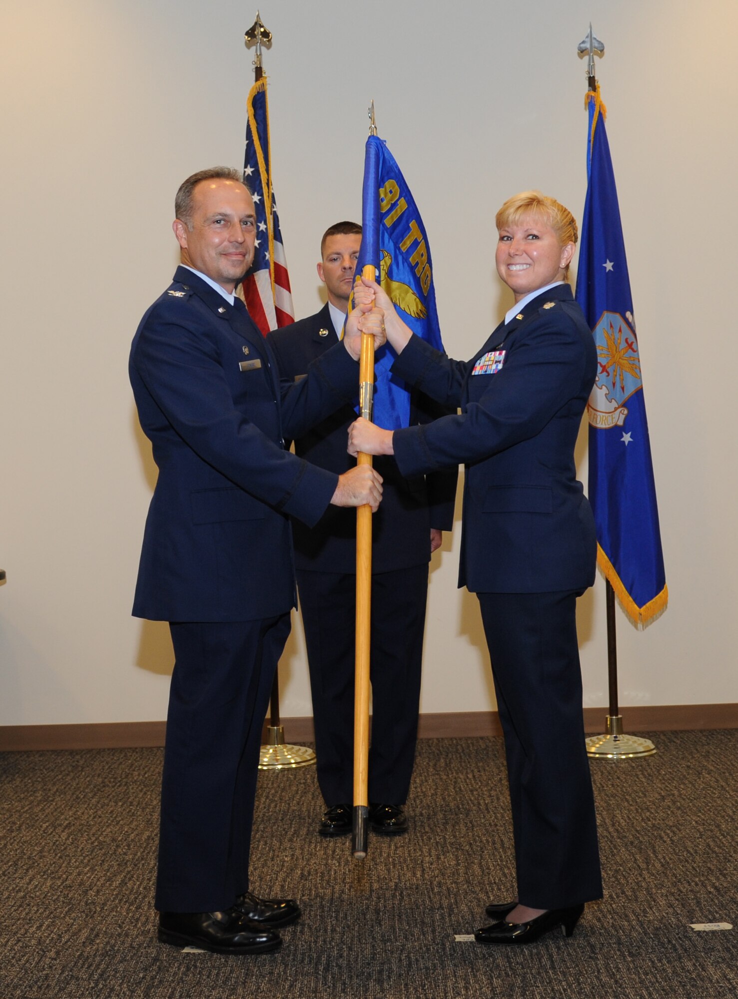 Col. George Tombe, 81st Training Group commander, passes the guidon to Lt. Col. Dorene Ross, as she assumes command of the 335th Training Squadron during the 335th TRS change of command ceremony July 22, 2013, at the Roberts Consolidated Aircraft Maintenance Facility, Keesler Air Force Base, Miss.  Lt. Col. Bradley McAlpine was the outgoing 335th TRS commander.  (U.S. Air Force photo by Kemberly Groue)