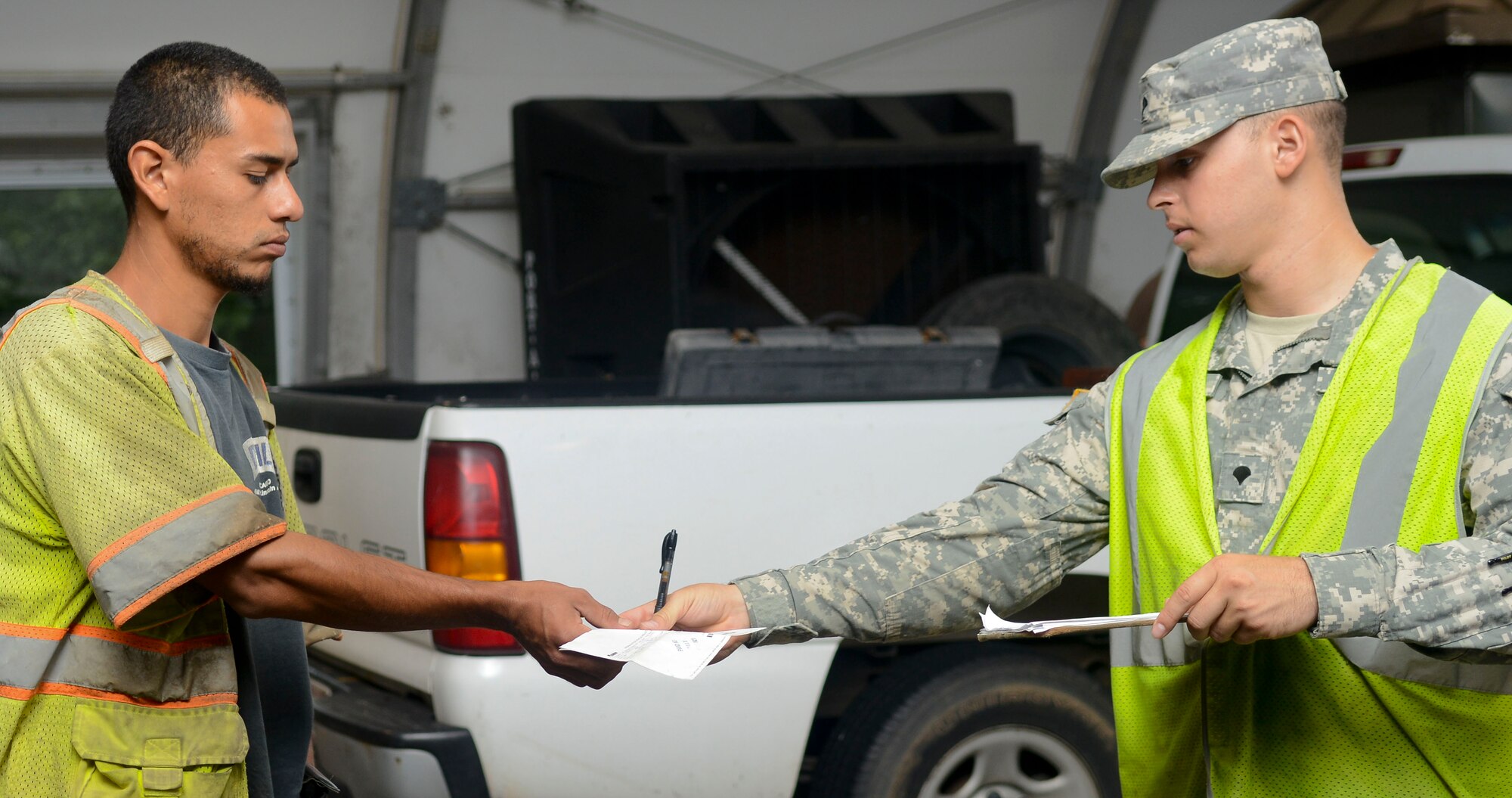 U.S. Army Spc. Angel Enchautegui, 7th Sustainment Brigade gate guard augmentee, returns a civilian’s information at Fort Eustis, Va., July 11, 2013. Roughly 7,000 vehicles pass through the Fort Eustis main gate every day. (U.S. Air Force Photo by Airman 1st Class Austin Harvill/Released)