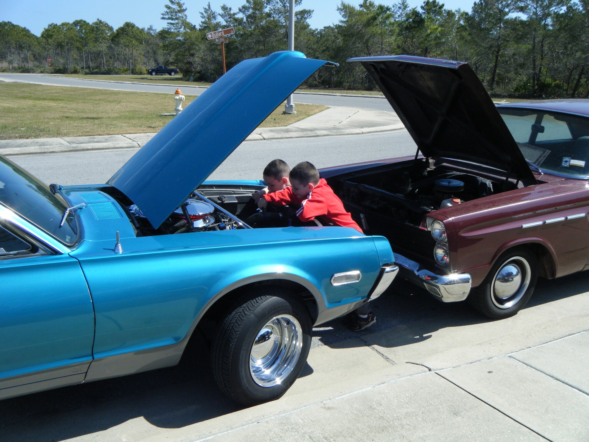 TYNDALL AIR FORCE BASE, Fla. -- At front, Grant and his twin brother Jack Shattuck share their father’s love for working on cars. The blue ’68 Mercury Cougar and the burgundy ’65 Mercury Comet were both completely restored by Chief Master Sgt. Trevor Shattuck. He plans to give the cars to his sons when they turn 16. (Courtesy photo)