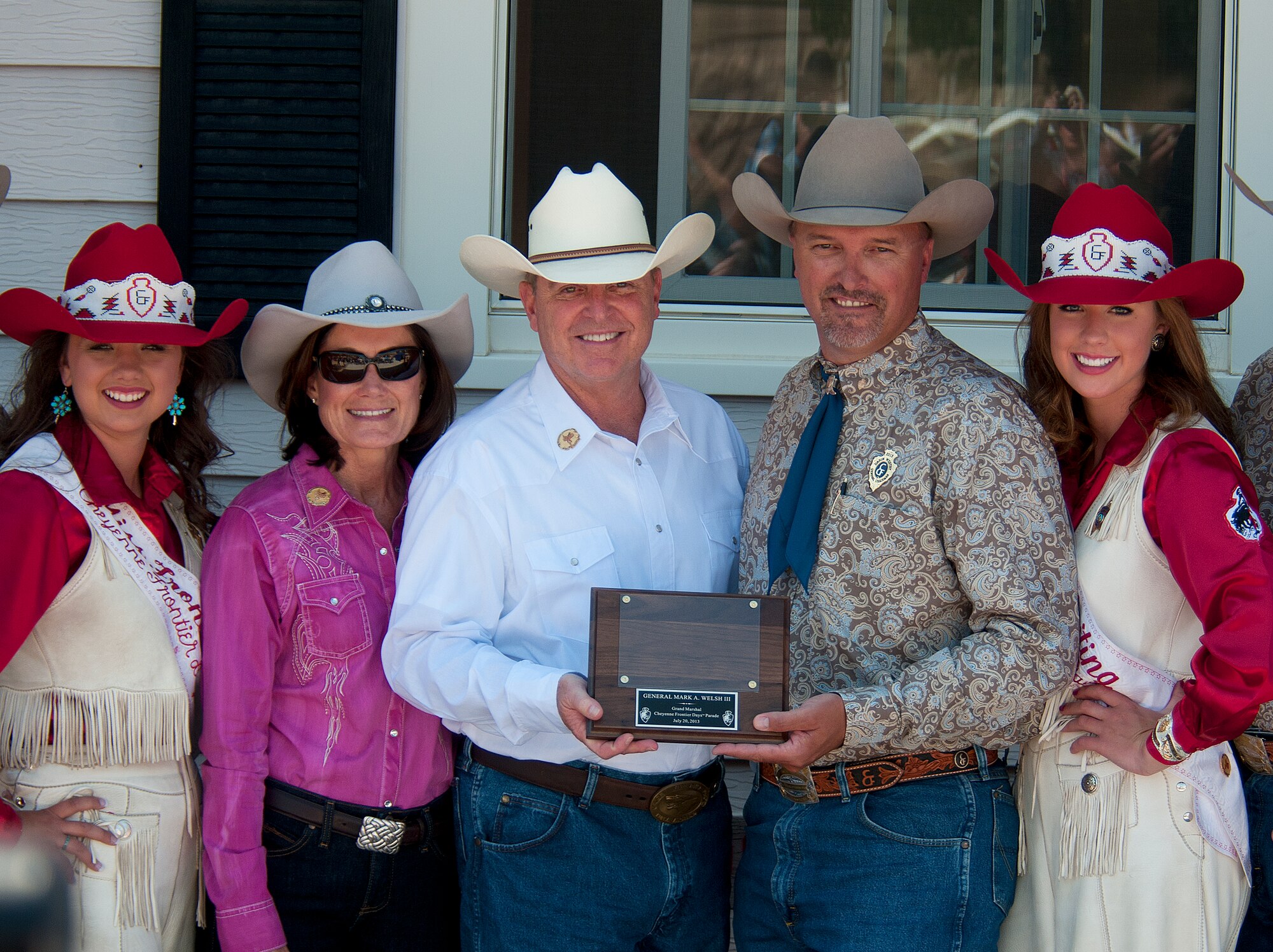 Air Force Chief of Staff Gen. Mark A. Welsh III receives a plaque from Cheyenne Frontier Days committee members, July 20, 2013, prior to the start of the 117th annual CFD parade as the general's wife, Betty; Chloe Pfoor, Miss Frontier; and Kaci Malmborg, her Lady-in-Waiting; look on. Welsh, who served as grand marshal for the opening parade, visited the region to participate in CFD events, but also to thank Airmen and the community for the continued service and support. (U.S. Air Force photo by R.J. Oriez)