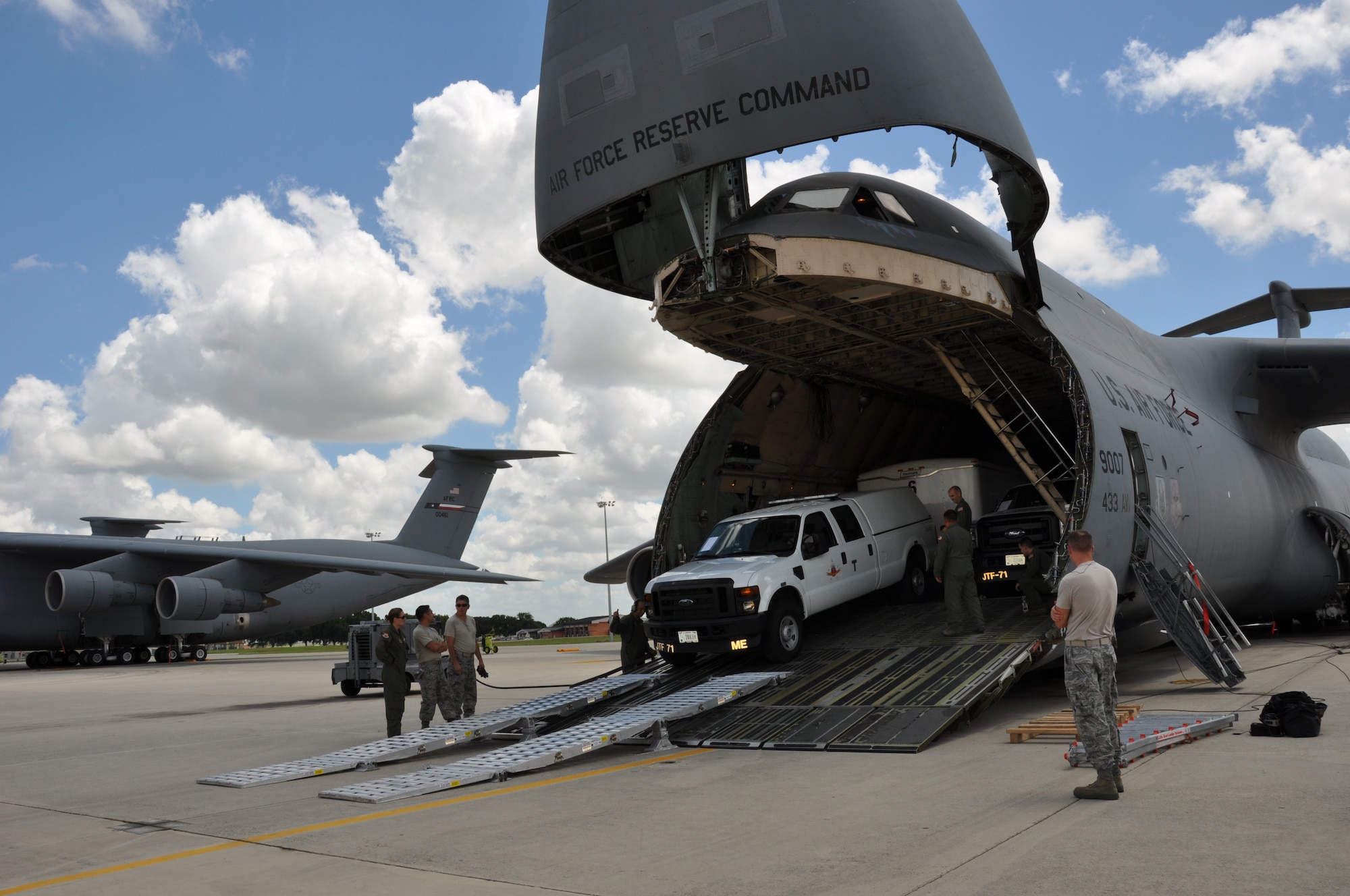 Members of the Consequence Management Team of the Texas Air National Guard drive their vehicles and trailers loaded with equipment off of a C-5 A Galaxy under the supervision of loadmasters from the 68th Airlift Squadron. The Texas Air Guardsmen, part of the Expeditionary Medical System, were trained on loading, securing and unloading their equipment from a 433rd Airlift Wing C-5A. (U.S. Air Force Photo by Tech. Sgt. Carlos Trevino)