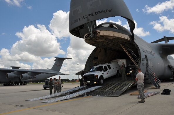 Members of the Consequence Management Team of the Texas Air National Guard drive their vehicles and trailers loaded with equipment off of a C-5 A Galaxy under the supervision of loadmasters from the 68th Airlift Squadron. The Texas Air Guardsmen, part of the Expeditionary Medical System, were trained on loading, securing and unloading their equipment from a 433rd Airlift Wing C-5A. (U.S. Air Force Photo by Tech. Sgt. Carlos Trevino)