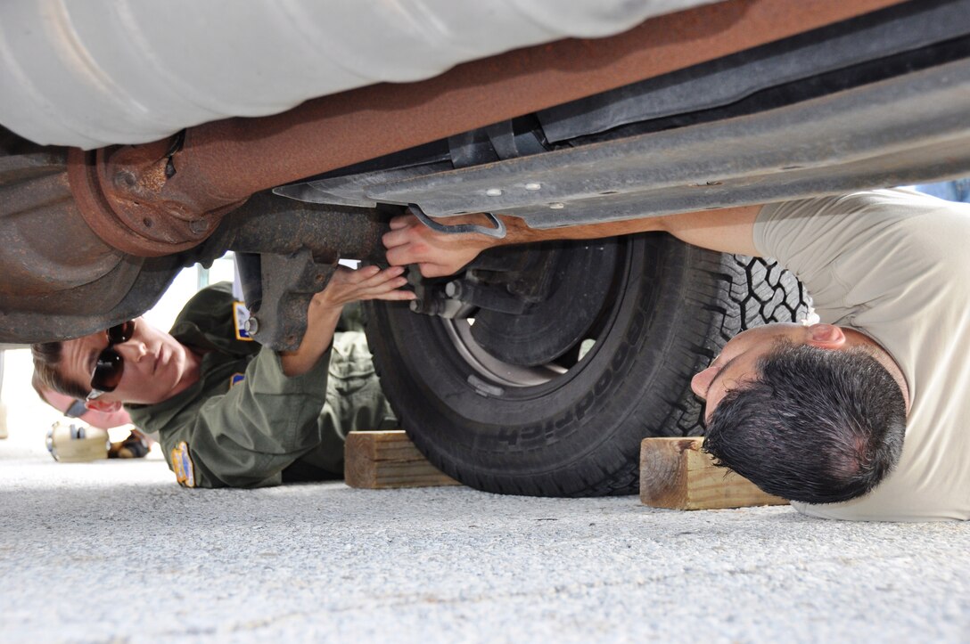 Staff Sgt. Rachel Jones (left), a load master with the 433rd Airlift Control Flight, shows Senior Airman Larry De Luna of the Texas Air National Guard Consequence Management Team where to attach hooks to the bottom of one of their trucks.  Guardsmen, part of the Expeditionary Medical System, received training on how load and secure vehicles onto a C-5 in case the Guard had to fly to a disaster area. (U.S. Air Force Photo by Tech. Sgt. Carlos J. Trevino)