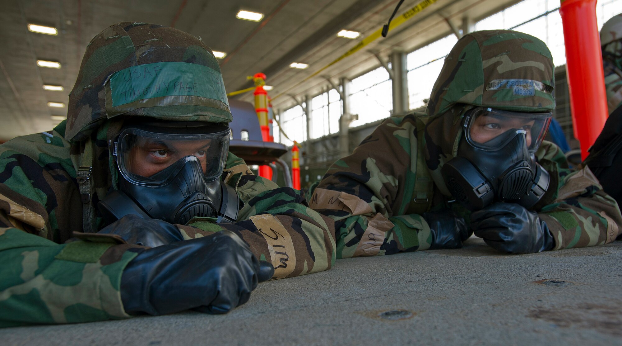 Members of the 15th Wing and the Hawaii Air National Guard 154th Wing take cover while in mission-oriented protective posture four at Hangar 13 during an Operational Readiness Exercise at Joint Base Pearl Harbor-Hickam, Hawaii, July 18, 2013. Both the 15th Wing and 154th HIANG Airmen participated in the readiness exercise that tested survival skills in a Total Force Integration environment during simulated stressful situations. (U.S. Air Force photo/Tech. Sgt. Jerome S. Tayborn)  