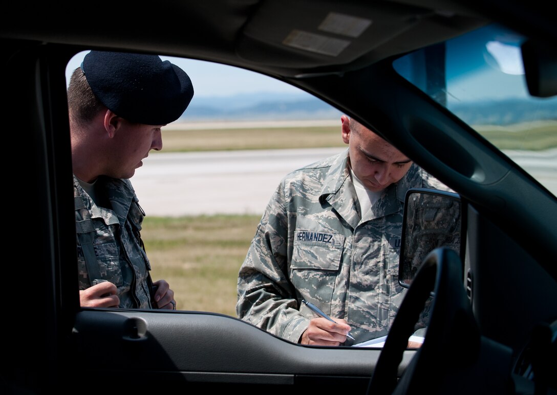 Airman 1st Class Steven Hernandez, 28th Operations Support Squadron Airfield Management operations coordinator, performs a spot check on Airman 1st Class Jeffery Reinke, 28th Security Forces Squadron patrolman, at Ellsworth Air Force Base, S.D., July 19, 2013. Spot checks are performed randomly twice a day to ensure that all personnel on the flightline have the proper documentation, training and authorization to be on the flightline. (U.S. Air Force photo by Airman 1st Class Alystria Maurer/Released)