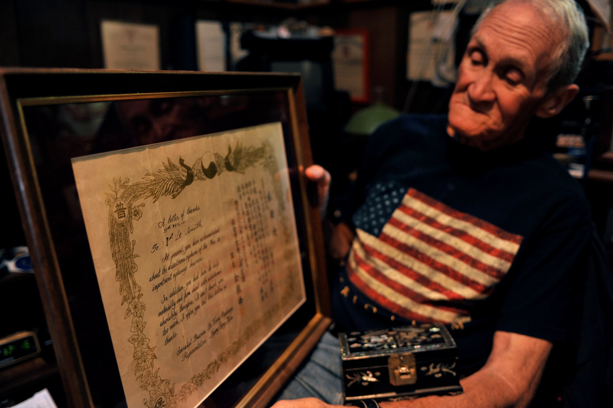Retired U.S. Army Maj. E. Vernon Smith Jr. looks at a framed letter of appreciation from a South Korean orphanage while in his home in central Virginia, July 20, 2013. Smith donated clothes and toys to the orphanage while stationed near the Korean demilitarized zone in 1956, and said seeing the impoverished children made him feel compelled to help. (U.S Air Force photo by Staff Sgt. Katie Gar Ward/Released) 